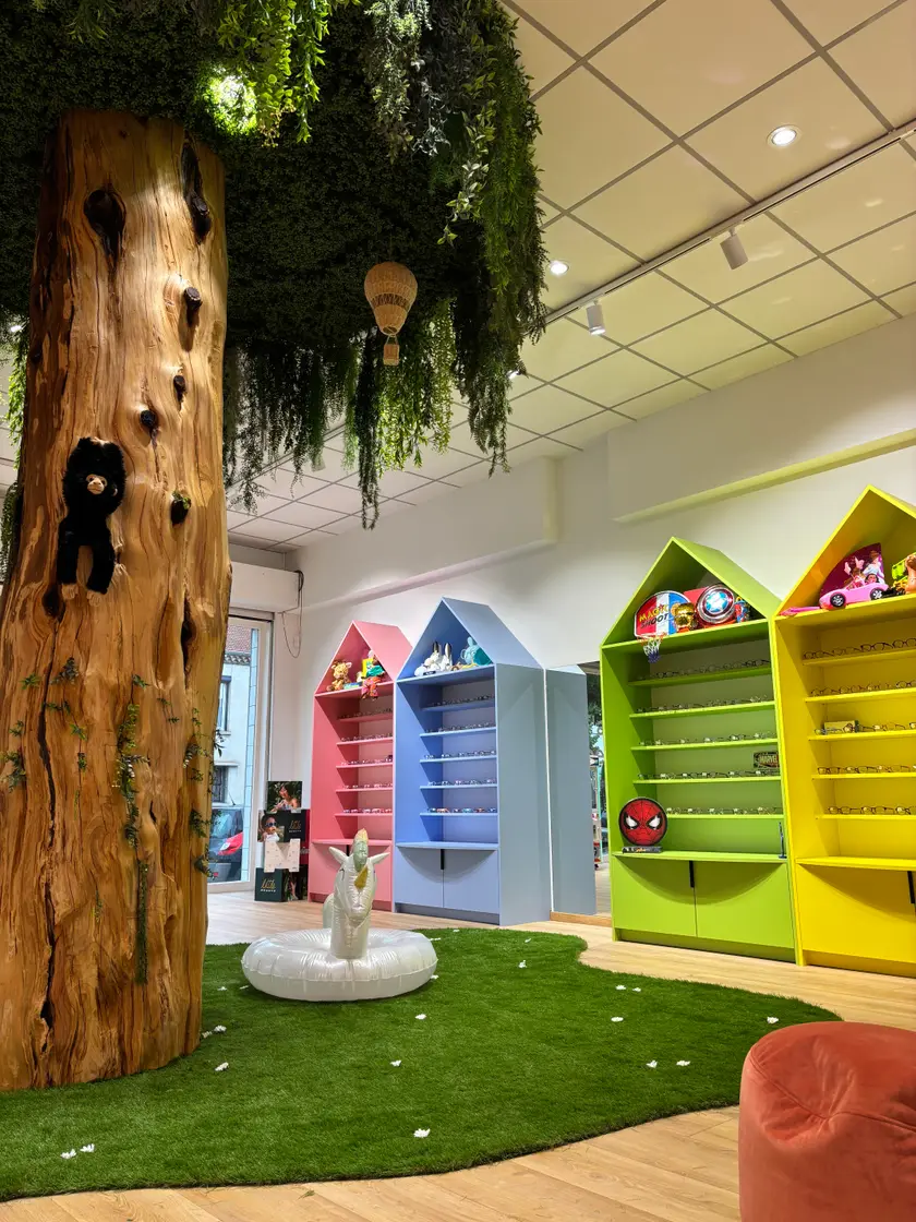 Le tronc de l'arbre vu de près, avec un ourson en peluche accroché à l'écorce et une montgolfière suspendue au feuillage.